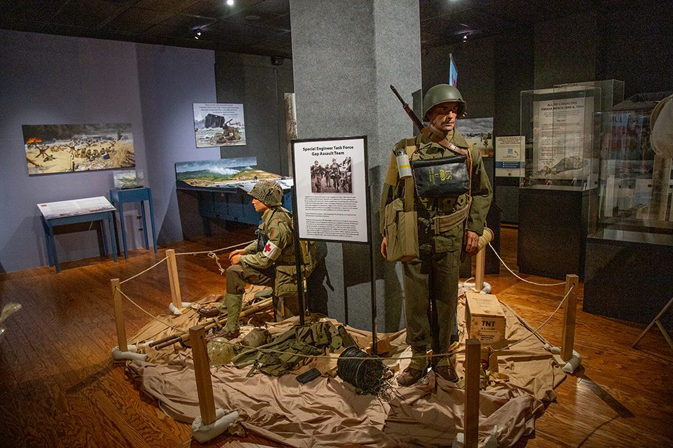 Gallery view of D-Day exhibit Gallery shot showing a sitting mannequin medic nd a standing soldier in D-day exhibit.